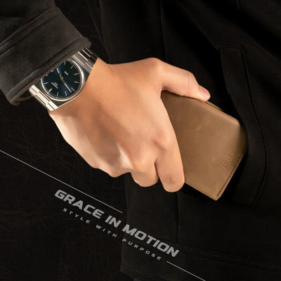 Hand holding a brown wallet with a black jacket and watch, featuring 'Grace in Motion' text.